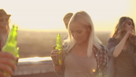 Young-girl-drinks-beer-and-moves-in-dance-with-friends.-She-enjoys-moments-and-her-eyes-closed